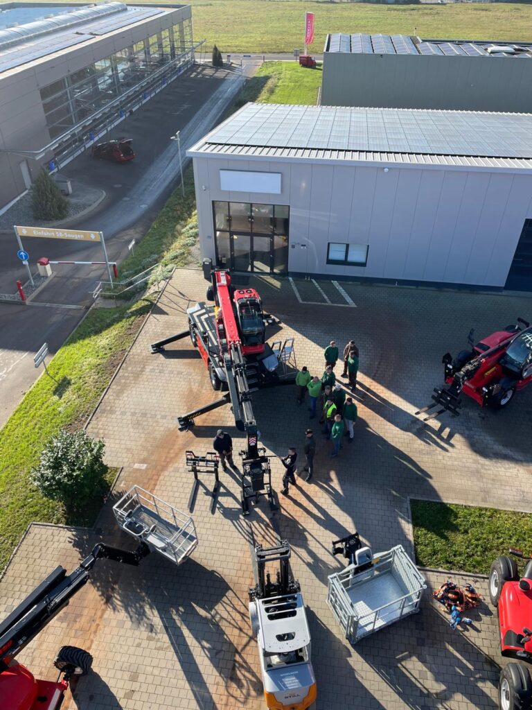 Vogelperspektive: Das Team der Schmidmeier NaturEnergie vor den Manitou Maschinen